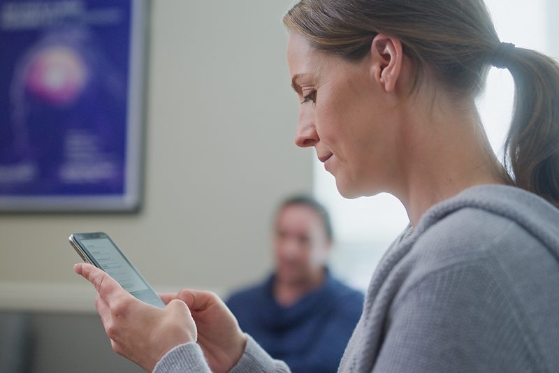 Woman on Her Phone Waiting for Her NeuroStar Assessment